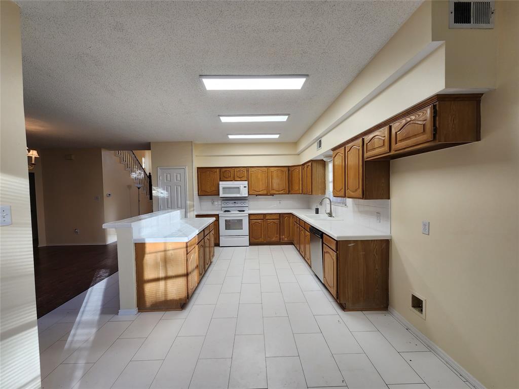 2413 Timber Ridge Lane Flower Mound, TX 75028 - Photo 11 of 32 Open-concept kitchen featuring wood-finish cabinetry, white countertops, a tiled backsplash, and recessed lighting