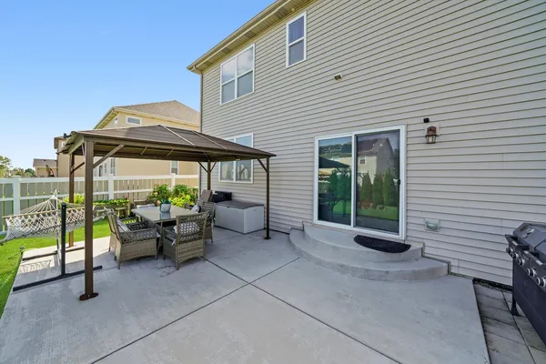 a backyard of a house with barbeque oven table and chairs