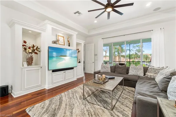 a living room with furniture kitchen view and a wooden floor