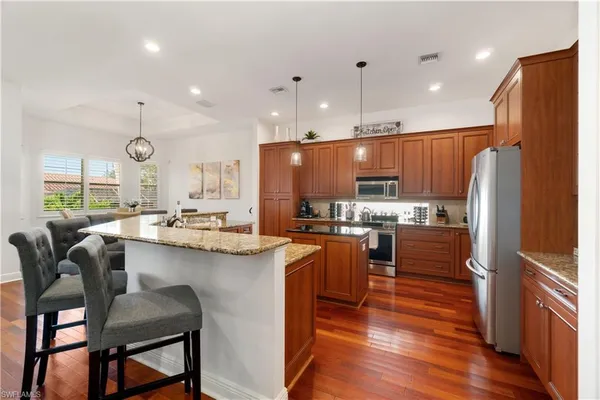 a kitchen with stainless steel appliances granite countertop a table chairs refrigerator and sink