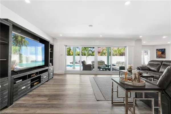 a living room with furniture a flat screen tv and a large window