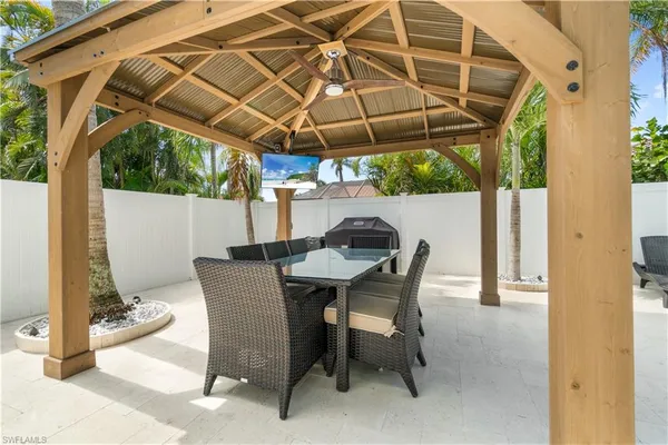 a view of patio with table and chairs under an umbrella with a small yard