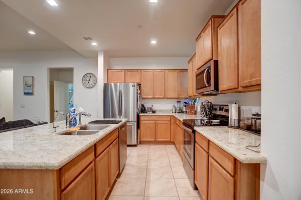 a kitchen with stainless steel appliances granite countertop a sink stove refrigerator and cabinets