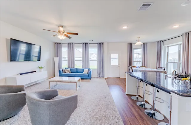 a living room with furniture a flat screen tv and a large window