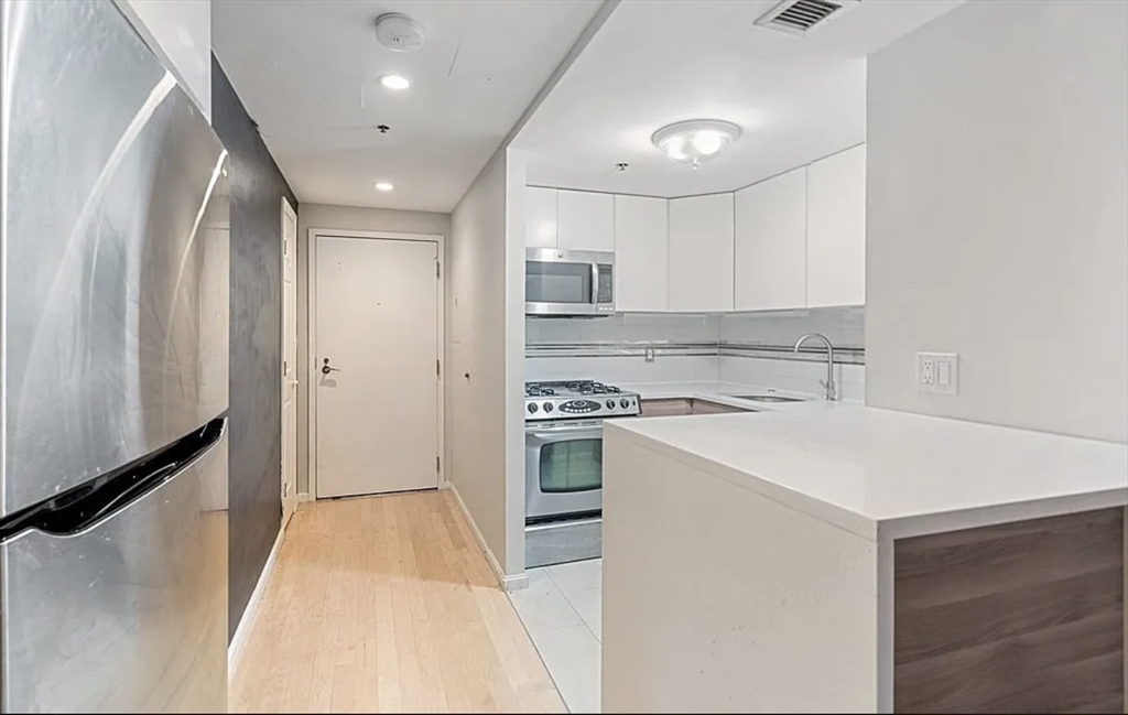 170 Tremont Street, Unit 905 Boston, MA 02111 - Photo 5 of 14 a kitchen with a stove a sink and a refrigerator