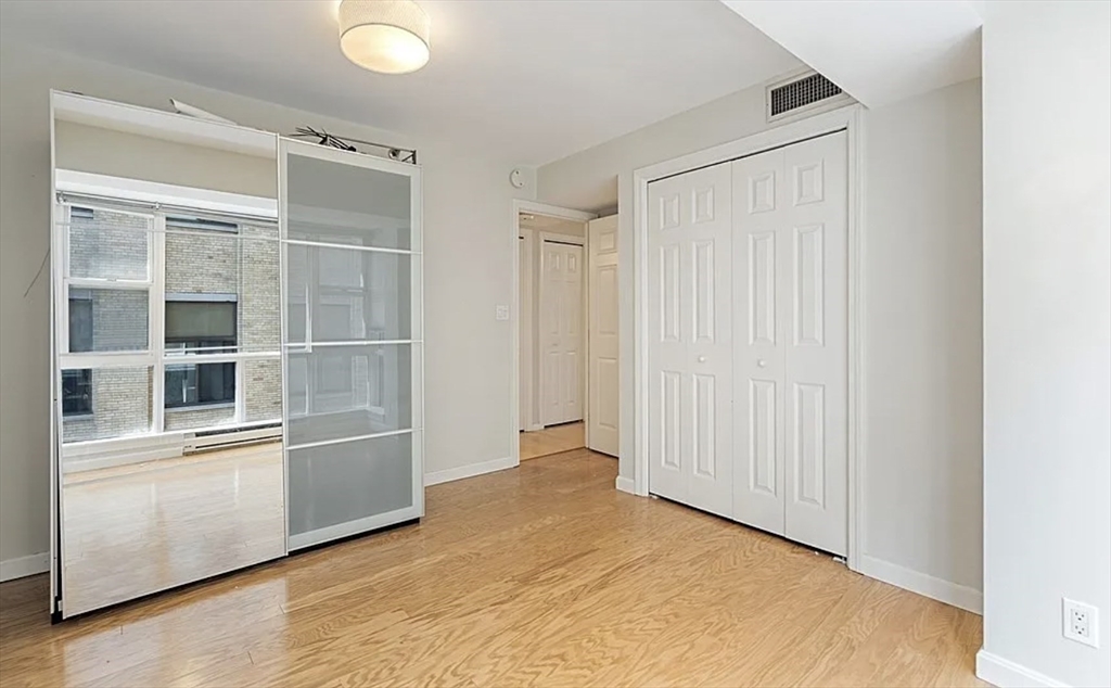 170 Tremont Street, Unit 905 Boston, MA 02111 - Photo 9 of 14 an empty room with wooden floor and windows