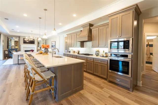 a kitchen with stainless steel appliances kitchen island granite countertop a stove a sink dishwasher a refrigerator and a dining table with wooden floor
