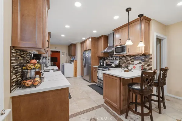 a kitchen with stainless steel appliances kitchen island granite countertop a sink and a refrigerator