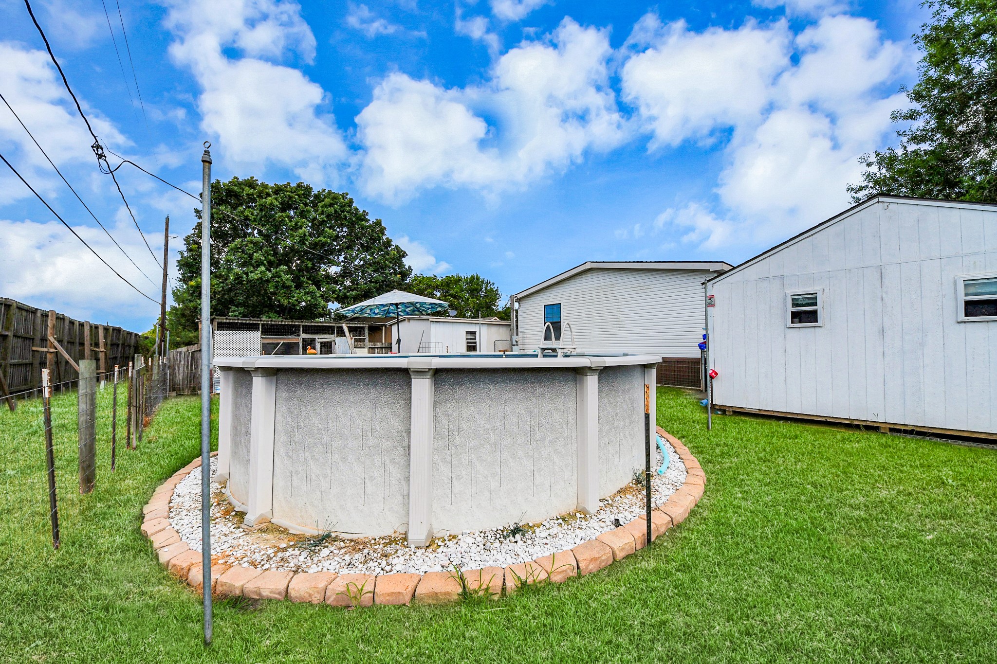 131 Kiowa Court Rosharon, TX 77583 - Photo 34 of 42 A serene backyard featuring an above-ground pool, and a separate storage shed. The area is fenced for privacy. Perfect for outdoor relaxation and entertainment.