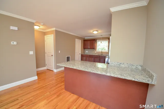 a view of a kitchen with kitchen island a sink wooden floor and a large window