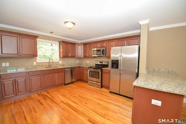 a kitchen with granite countertop a refrigerator and wooden cabinets