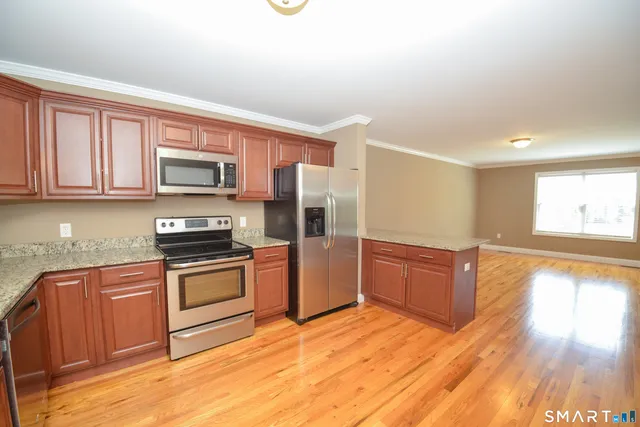 a kitchen with stainless steel appliances granite countertop a stove a sink dishwasher a microwave oven and a refrigerator with wooden floor