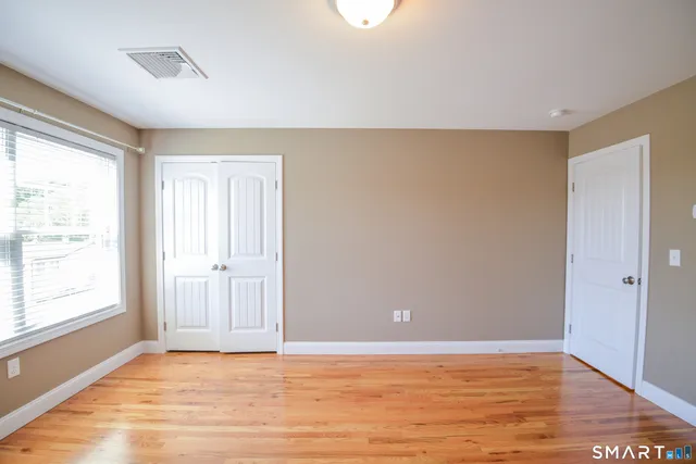 a view of an empty room with window and wooden floor