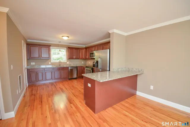 a large kitchen with wooden floor and stainless steel appliances