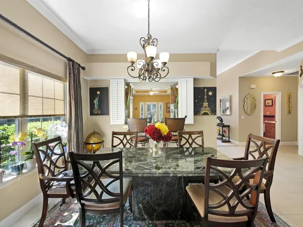 a view of a dining room with furniture a chandelier and large windows