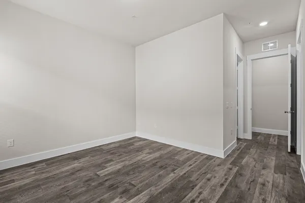 a view of an empty room with wooden floor and closet