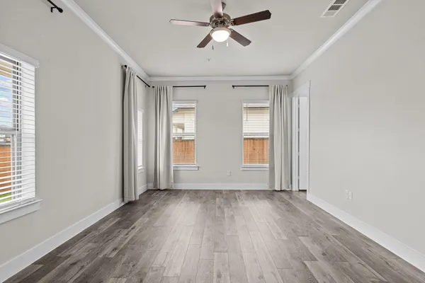a view of empty room with wooden floor and fan