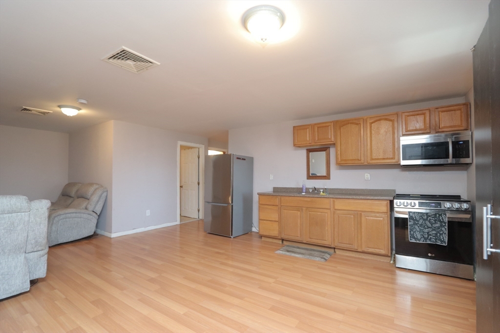 205 Elm Street Westfield, MA 01085 - Photo 8 of 24 a large kitchen with stainless steel appliances granite countertop a stove a sink dishwasher and a refrigerator with wooden floor