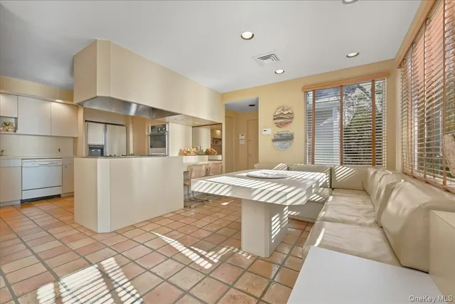 a living room with a large window couches and kitchen view