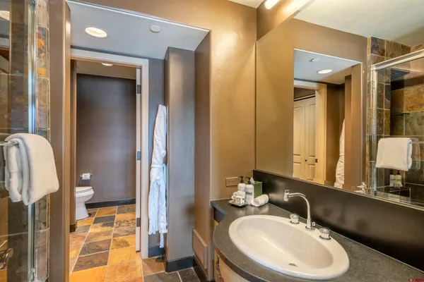 a bathroom with a granite countertop toilet sink and mirror
