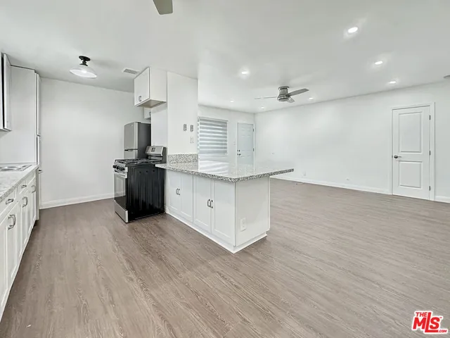 a kitchen with stainless steel appliances granite countertop a sink a stove and a wooden floors