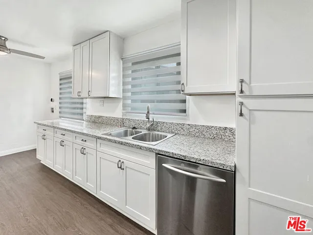 a kitchen with stainless steel appliances granite countertop a sink and dishwasher with white cabinets