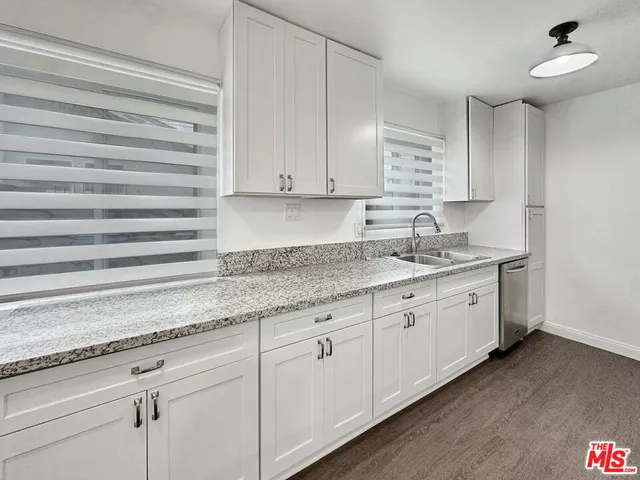 a kitchen with granite countertop white cabinets and a sink