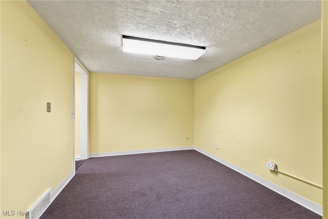 1817 Fulton Road Northwest Canton, OH 44709 - Photo 23 of 25 Unfurnished room featuring a textured ceiling and dark carpet
