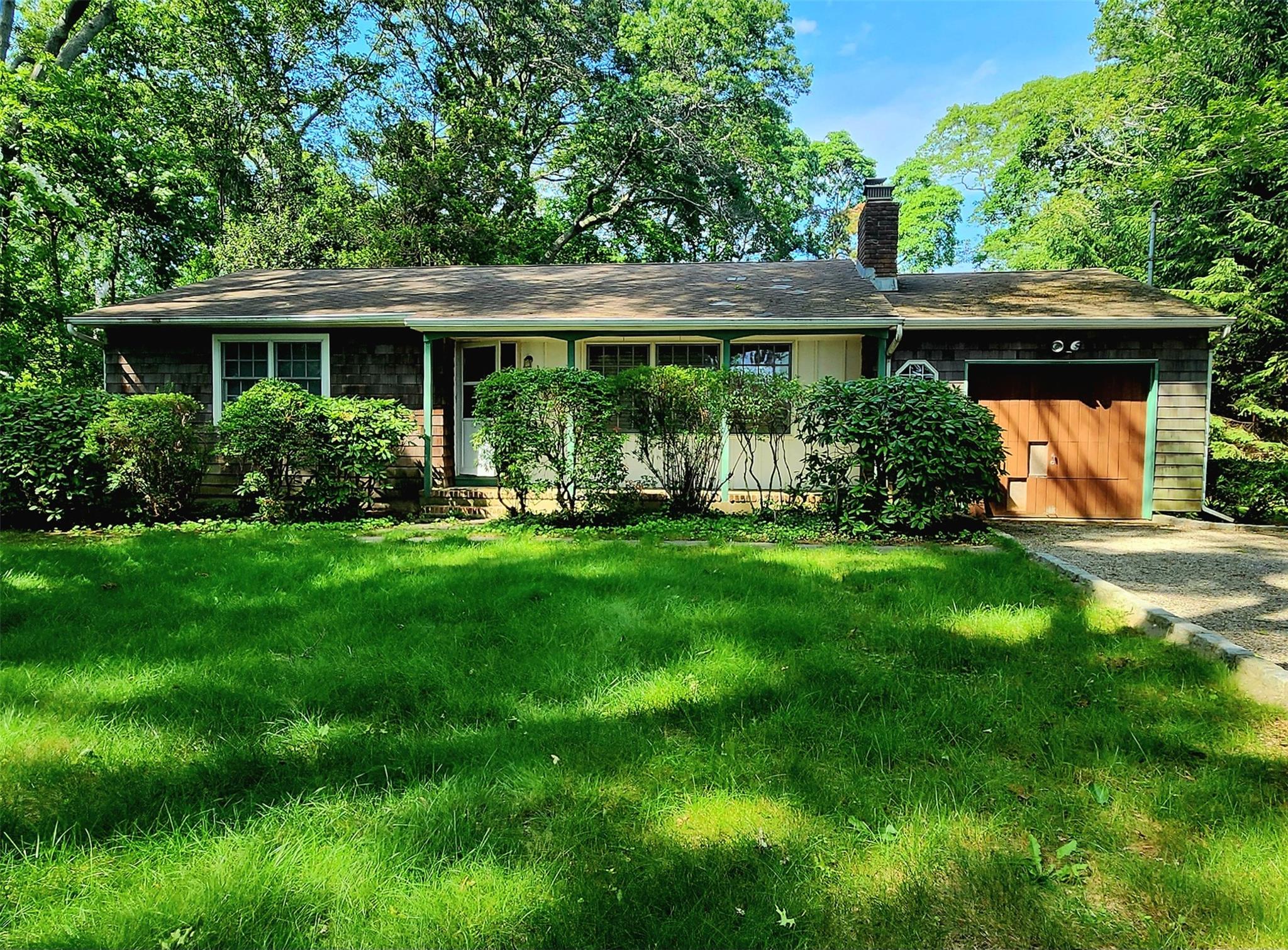 Ranch-style house with attached garage, driveway, and a front lawn