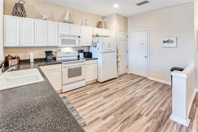 a kitchen with granite countertop white cabinets and white appliances