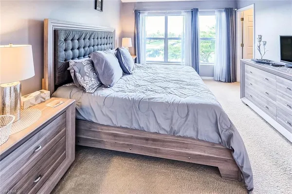 a bedroom with a bed and a flat tv screen on dresser