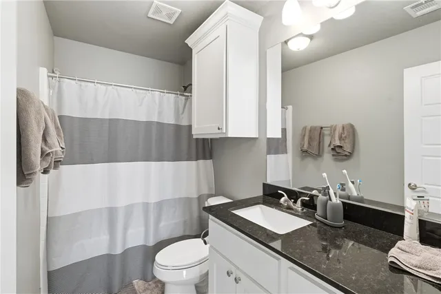 a bathroom with a granite countertop sink a toilet and bathtub