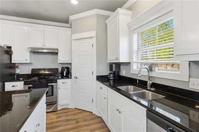 a kitchen with granite countertop a sink a stove and cabinets