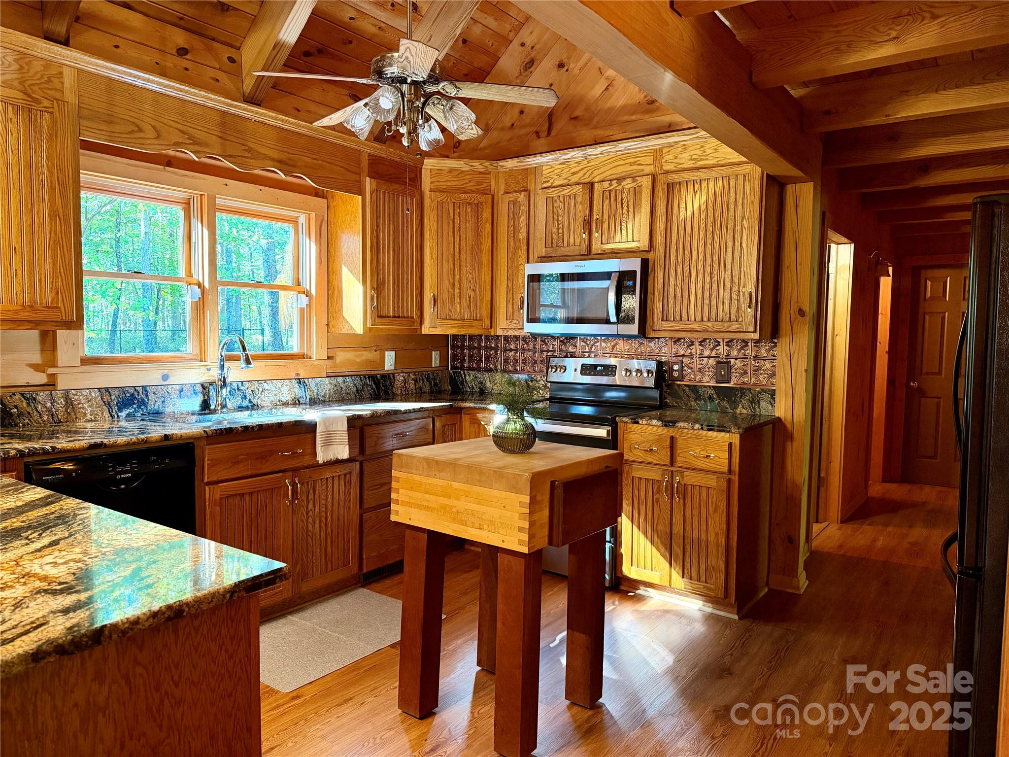 565 Barber Road Gold Hill, NC 28071 - Photo 12 of 42 a kitchen with stainless steel appliances granite countertop a stove a refrigerator a sink a dining table and chairs with wooden floor