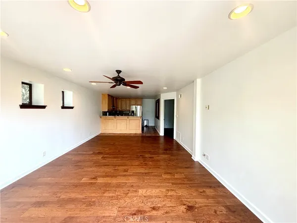 a view of a living room with kitchen furniture and a ceiling fan