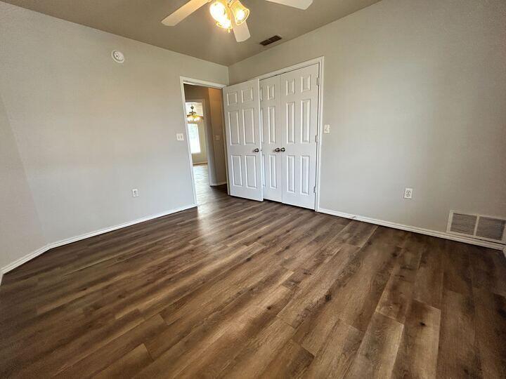 1116 82nd Street, Unit B Lubbock, TX 79423 - Photo 8 of 13 a view of an empty room with wooden floor and a ceiling fan