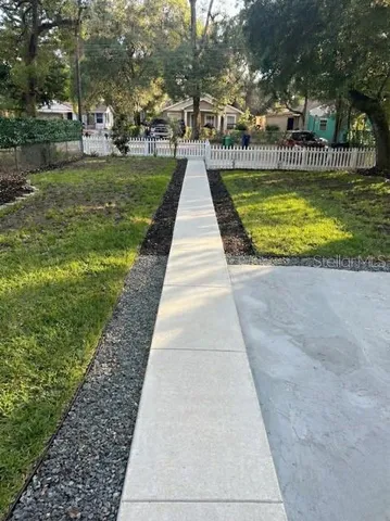 a view of swimming pool that has lawn chairs with plants and trees