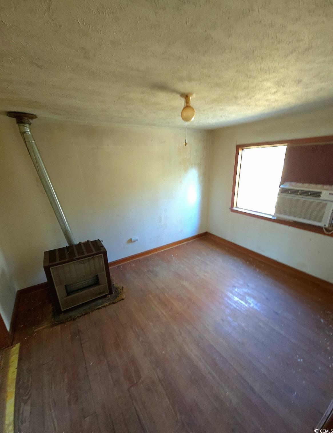 150 Landmark Road Conway, SC 29527 - Photo 12 of 35 Empty room featuring hardwood / wood-style flooring, a wood stove, a textured ceiling, cooling unit, and heating unit