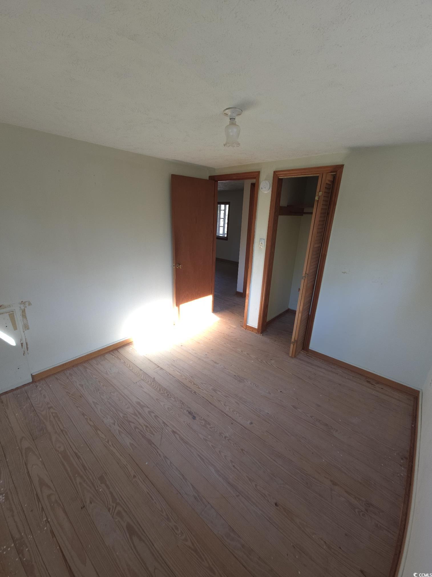 150 Landmark Road Conway, SC 29527 - Photo 17 of 35 Unfurnished bedroom with a closet, wood finished floors, and a textured ceiling