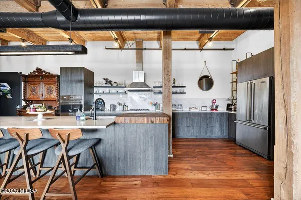 a kitchen with stainless steel appliances kitchen island granite countertop a table chairs in it and wooden floors