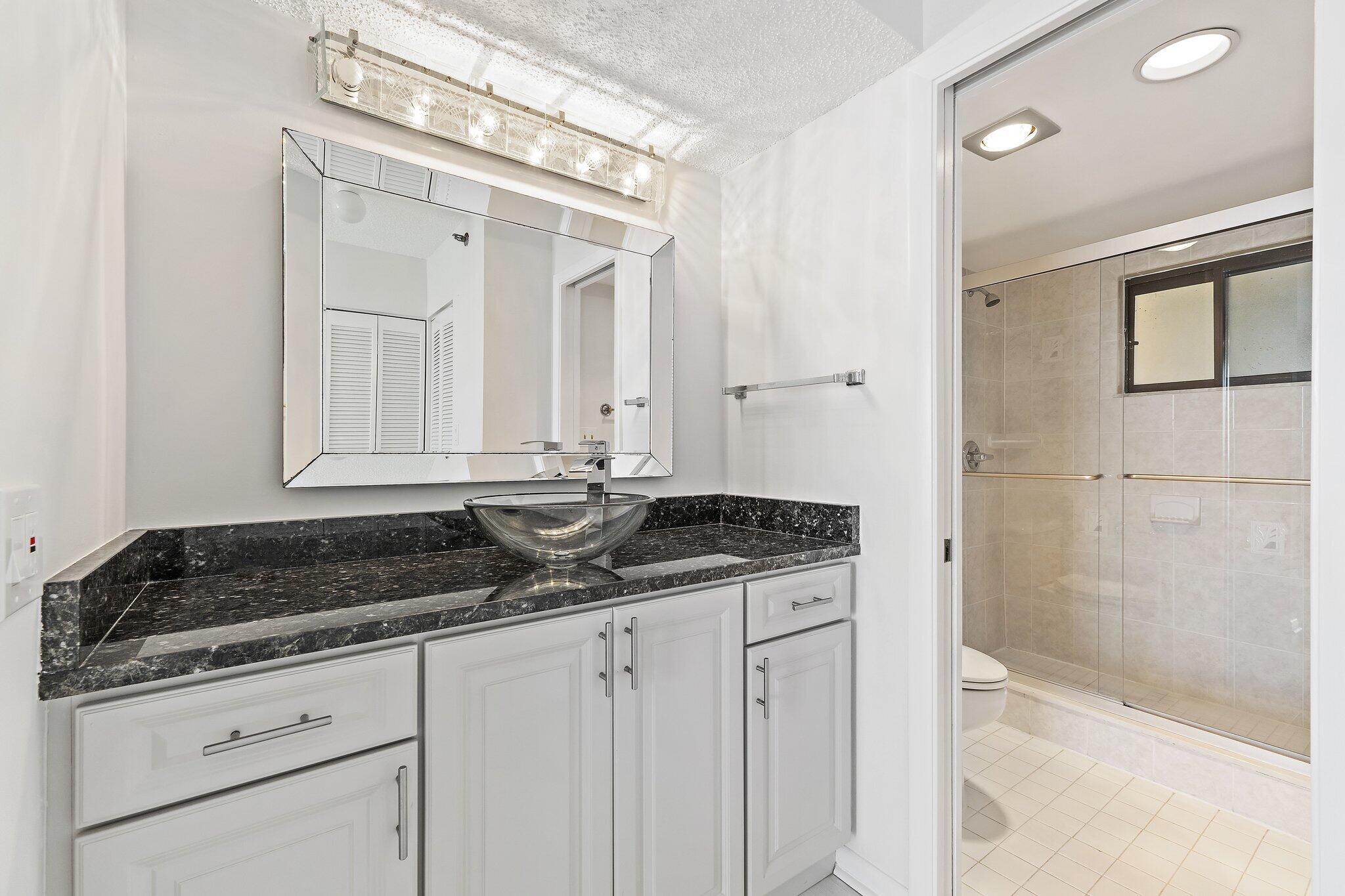 300 Ocean Trail Way, Unit 1406 Jupiter, FL 33477 - Photo 29 of 42 a bathroom with a granite countertop sink a mirror and shower