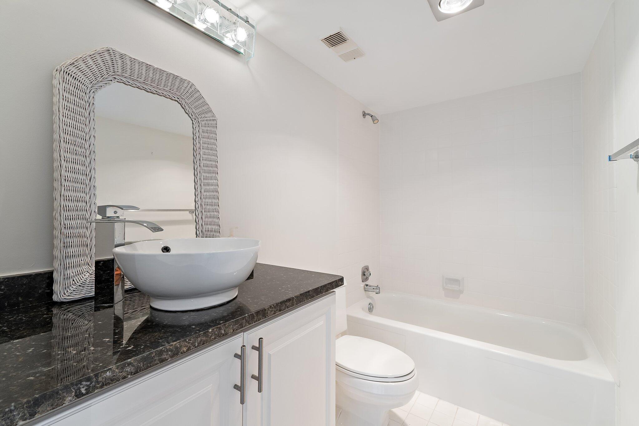 300 Ocean Trail Way, Unit 1406 Jupiter, FL 33477 - Photo 34 of 42 a bathroom with a granite countertop sink mirror toilet and bathtub