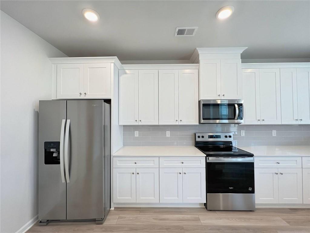2790 Dolce Road Dacula, GA 30019 - Photo 18 of 66 a kitchen with stainless steel appliances a refrigerator stove and white cabinets