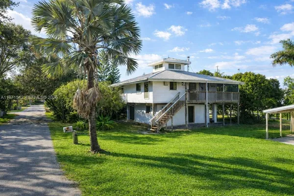 a front view of a house with garden and trees