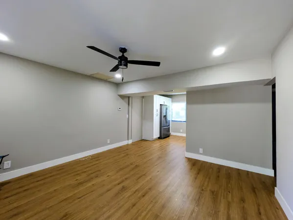 an empty room with wooden floor and a ceiling fan