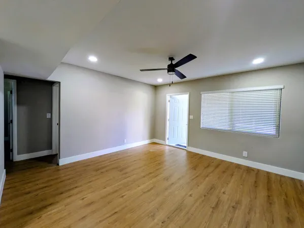 a view of an empty room with wooden floor and a window