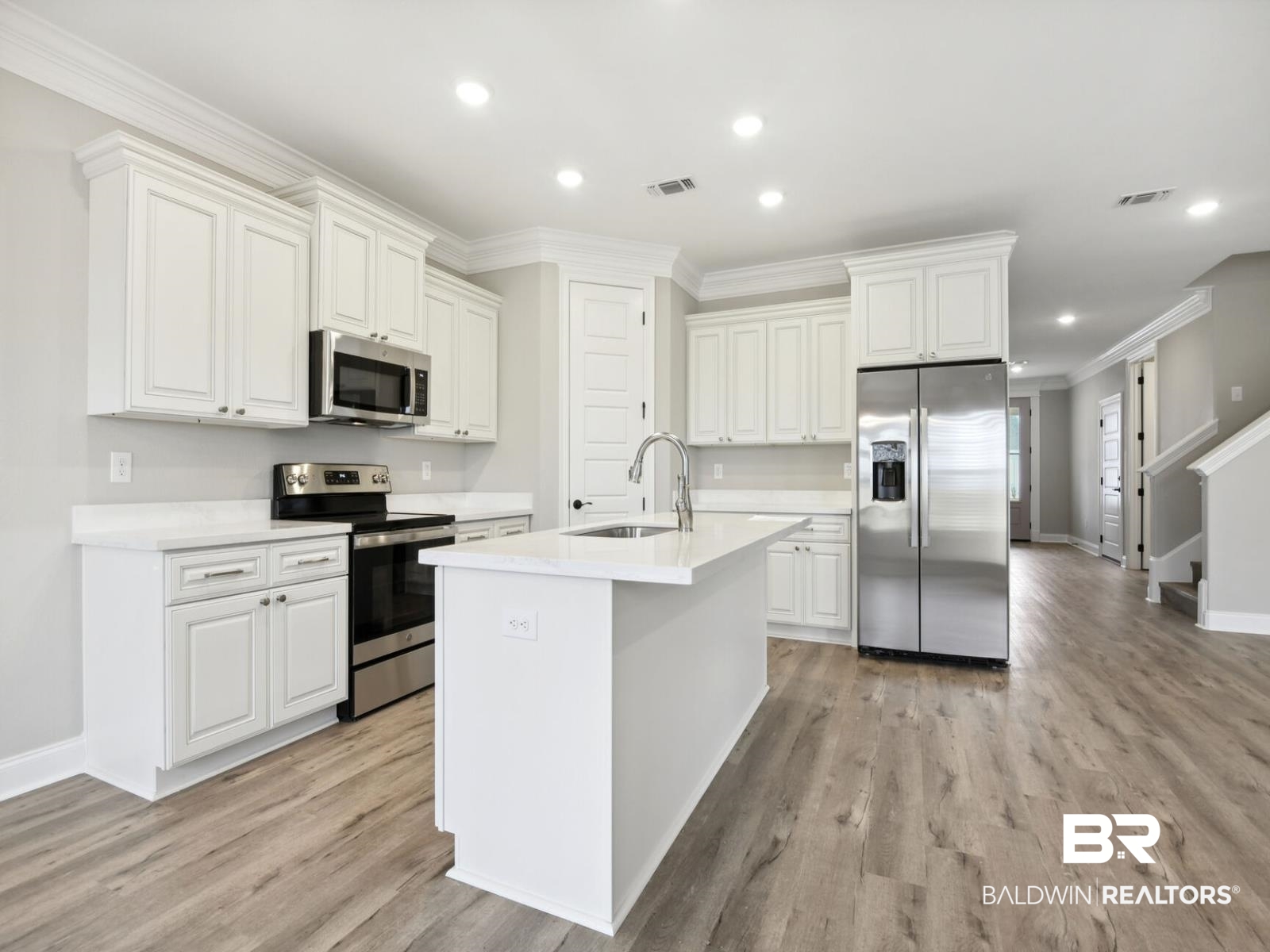 12922 Gondala Street Elberta, AL 36530 - Photo 12 of 20 Kitchen featuring stainless steel appliances, white cabinets, crown molding, recessed lighting, and a kitchen island with sink