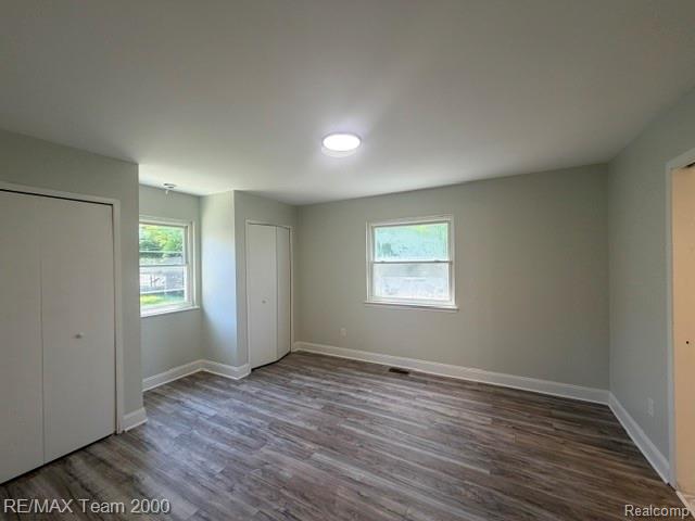580 Palmerston Street River Rouge, MI 48218 - Photo 11 of 19 Interior room featuring wood-finish flooring, two windows, two built-in closets with bi-fold doors, and a ceiling-mounted light fixture