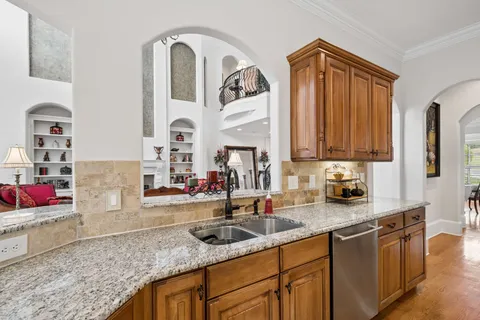 a kitchen with granite countertop a stove a sink and dishwasher wooden cabinets with granite countertops