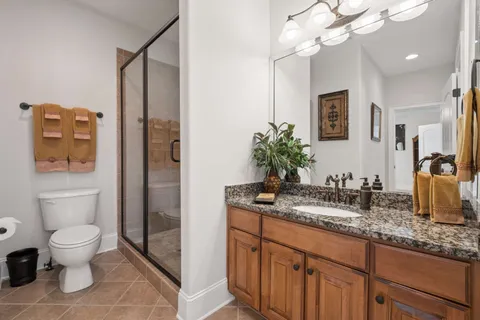 a bathroom with a granite countertop sink a toilet and mirror